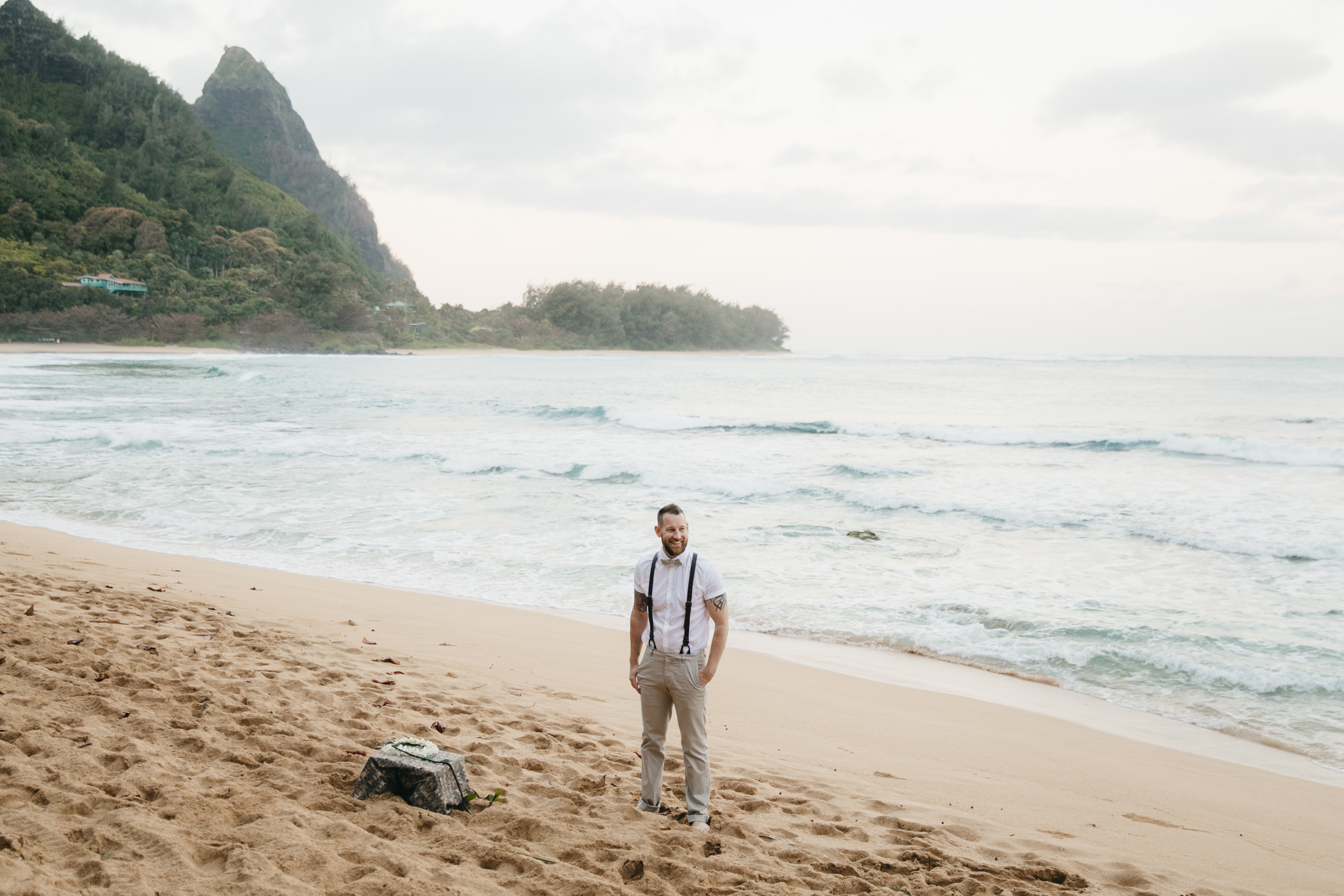 A groom waits for his bride on Tunnels Beach Kauai during adventure elopement by photographer Colby and Jess