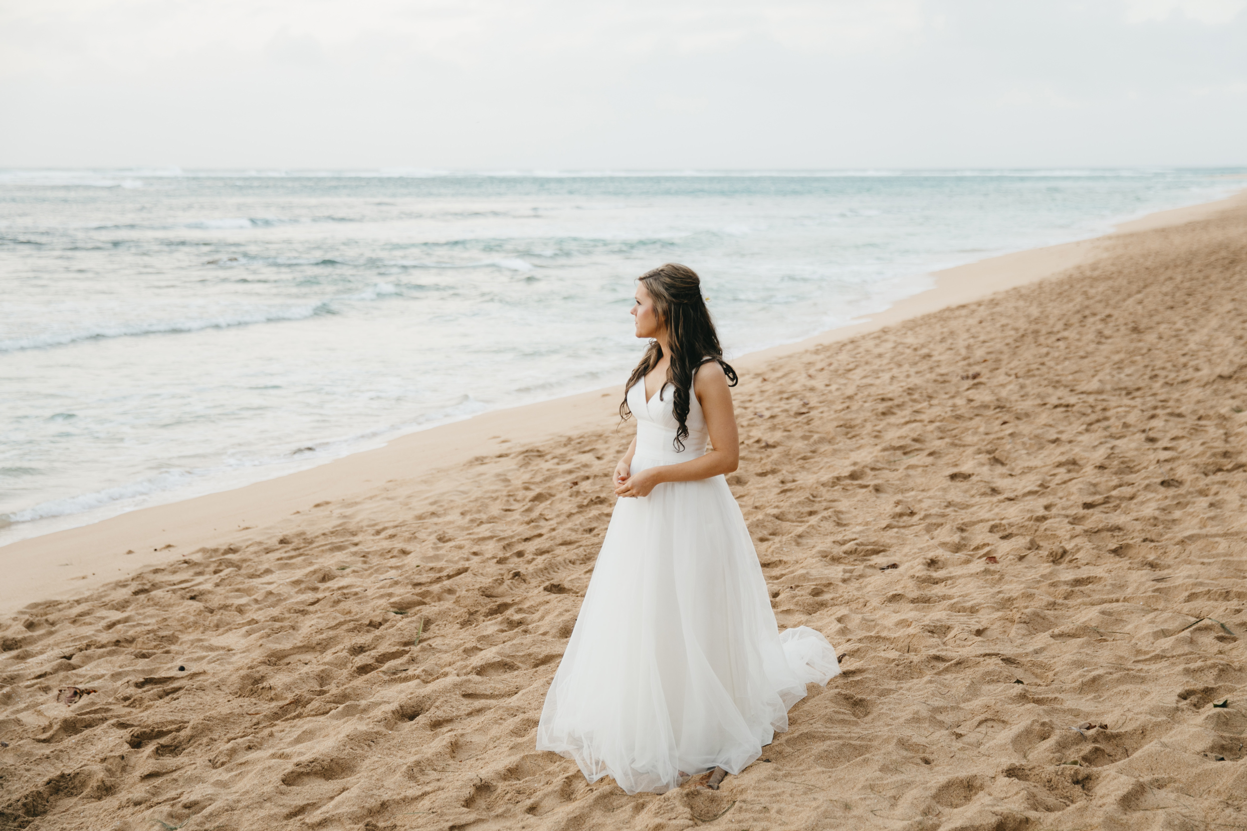 Bride stands on Tunnels Beach during Kauai Elopement by Adventure Wedding photographers Colby and Jess