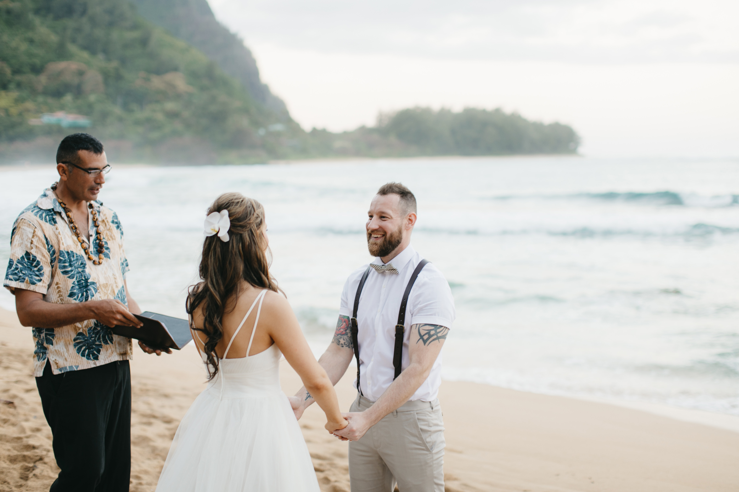 Bride and groom exchange vows during Tunnels Beach wedding ceremony with Kauai Elopement Photographers Colby and Jess