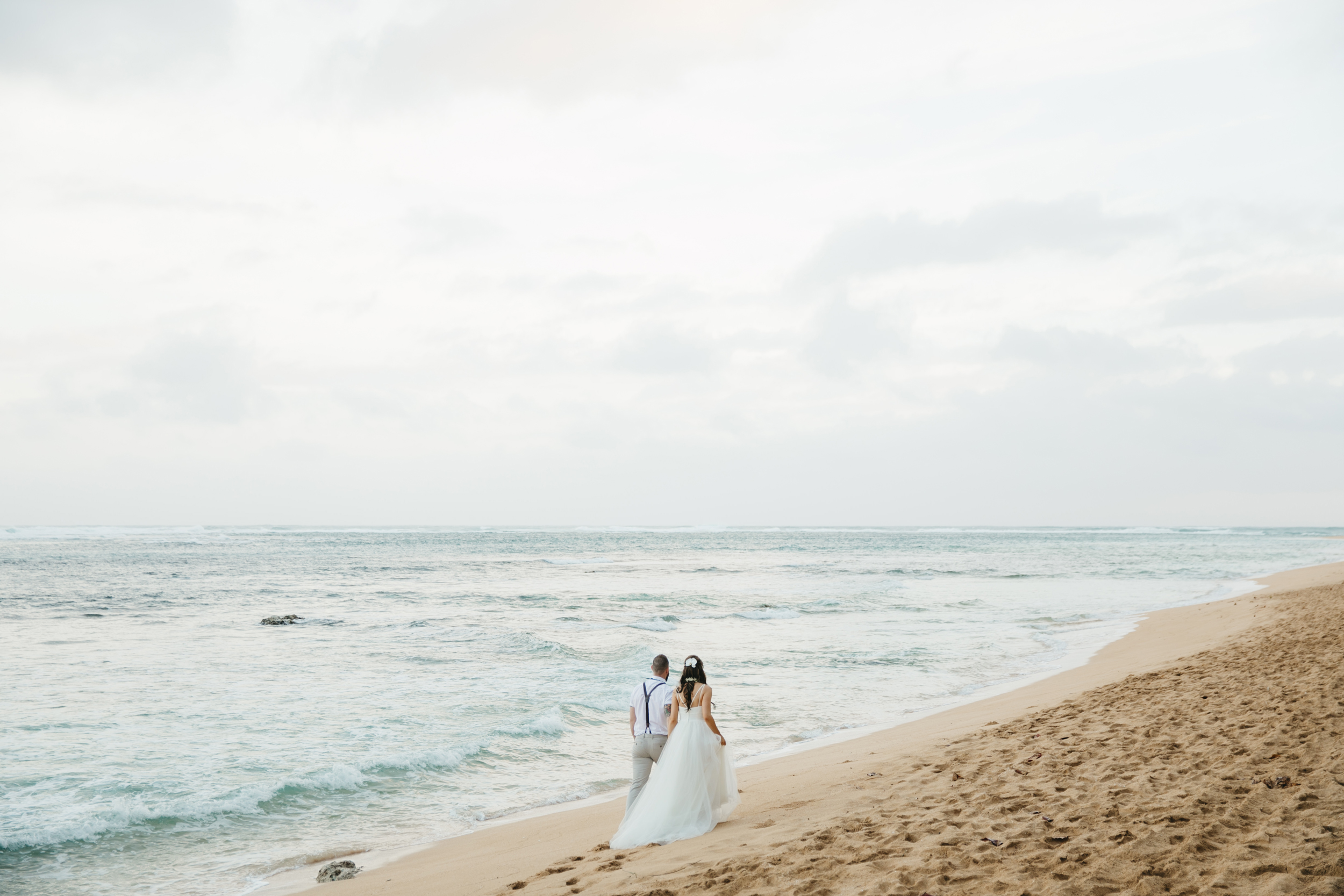 A couple walks on the beach after Tunnels Beach Elopement Ceremony by Kauai Wedding Photographers Colby and Jess