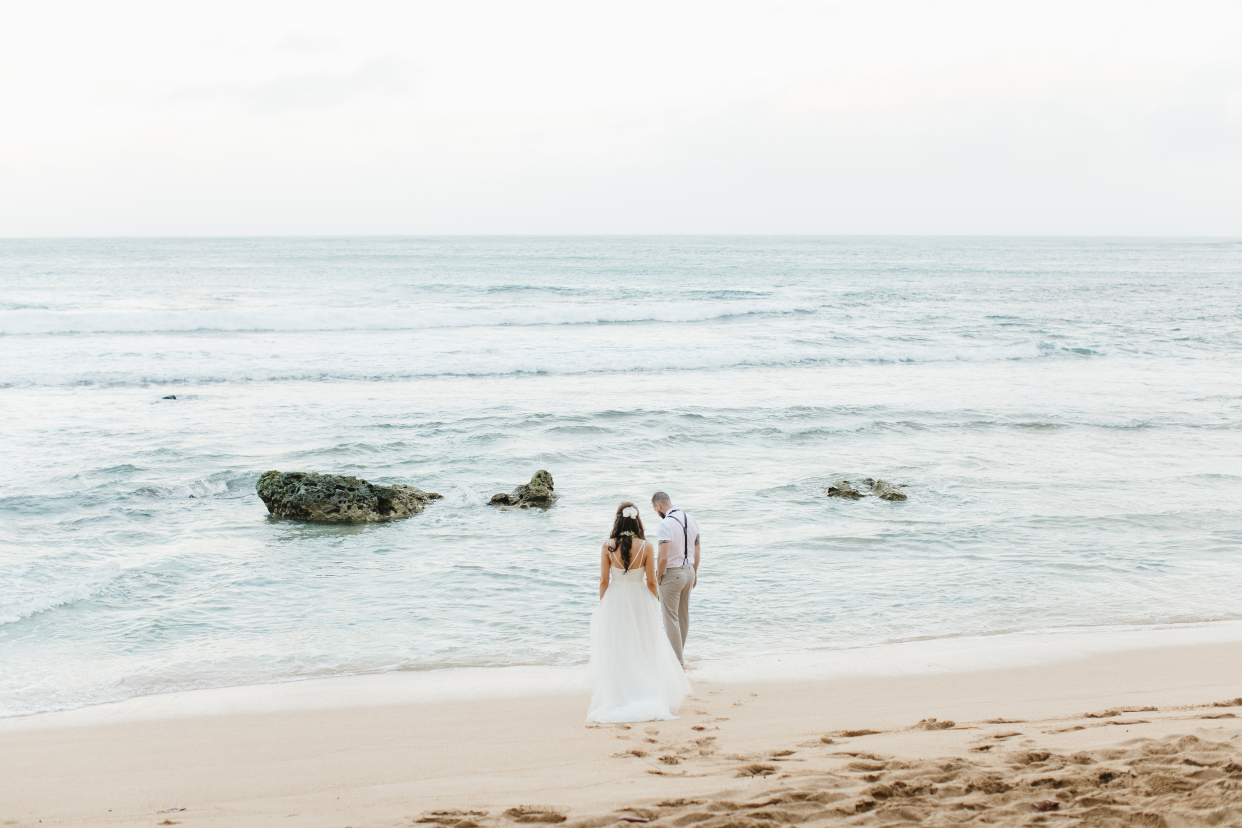 A couple walks on the beach after Tunnels Beach Elopement Ceremony by Kauai Wedding Photographers Colby and Jess