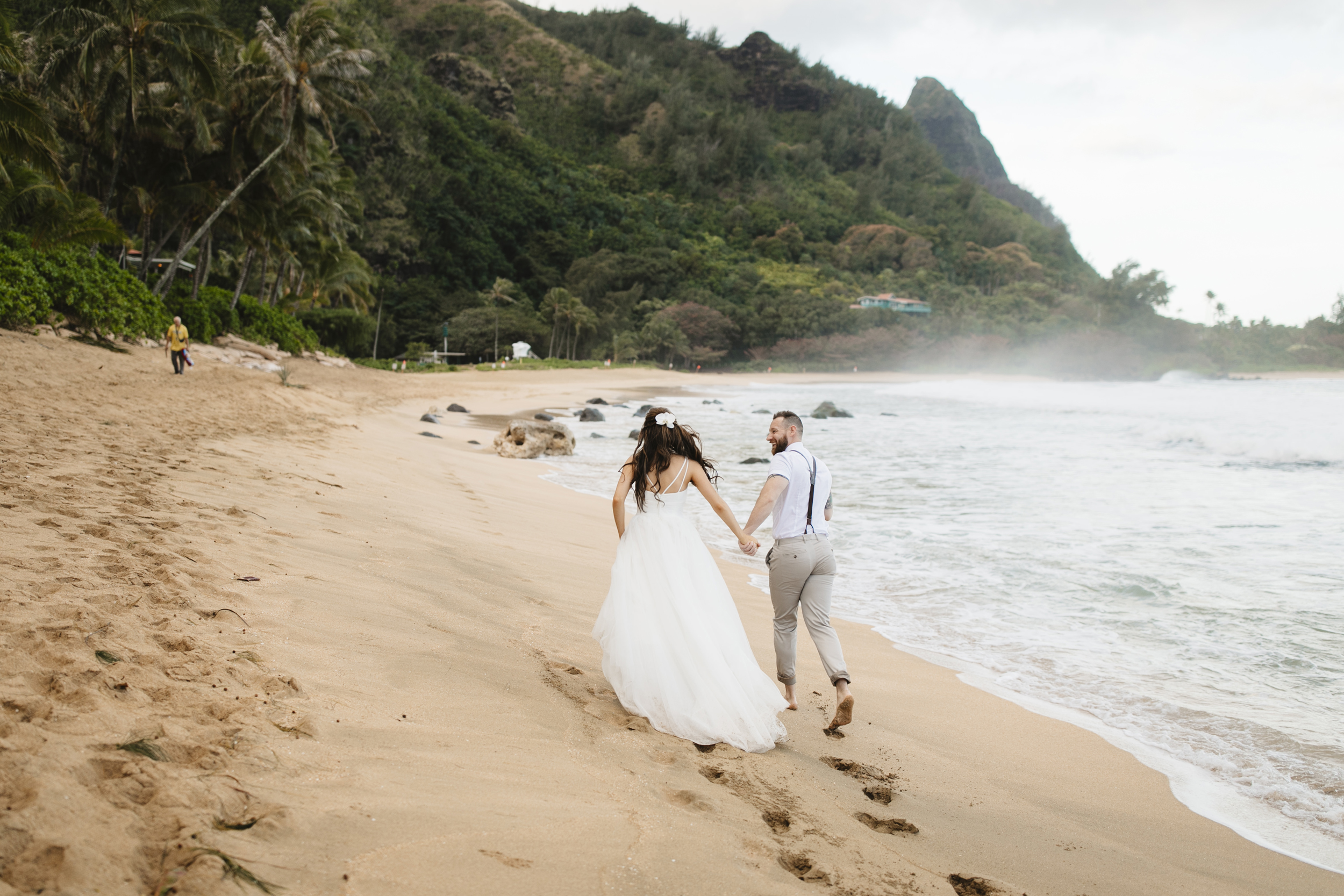 A couple runs on the beach after Tunnels Beach Elopement Ceremony by Kauai Wedding Photographers Colby and Jess