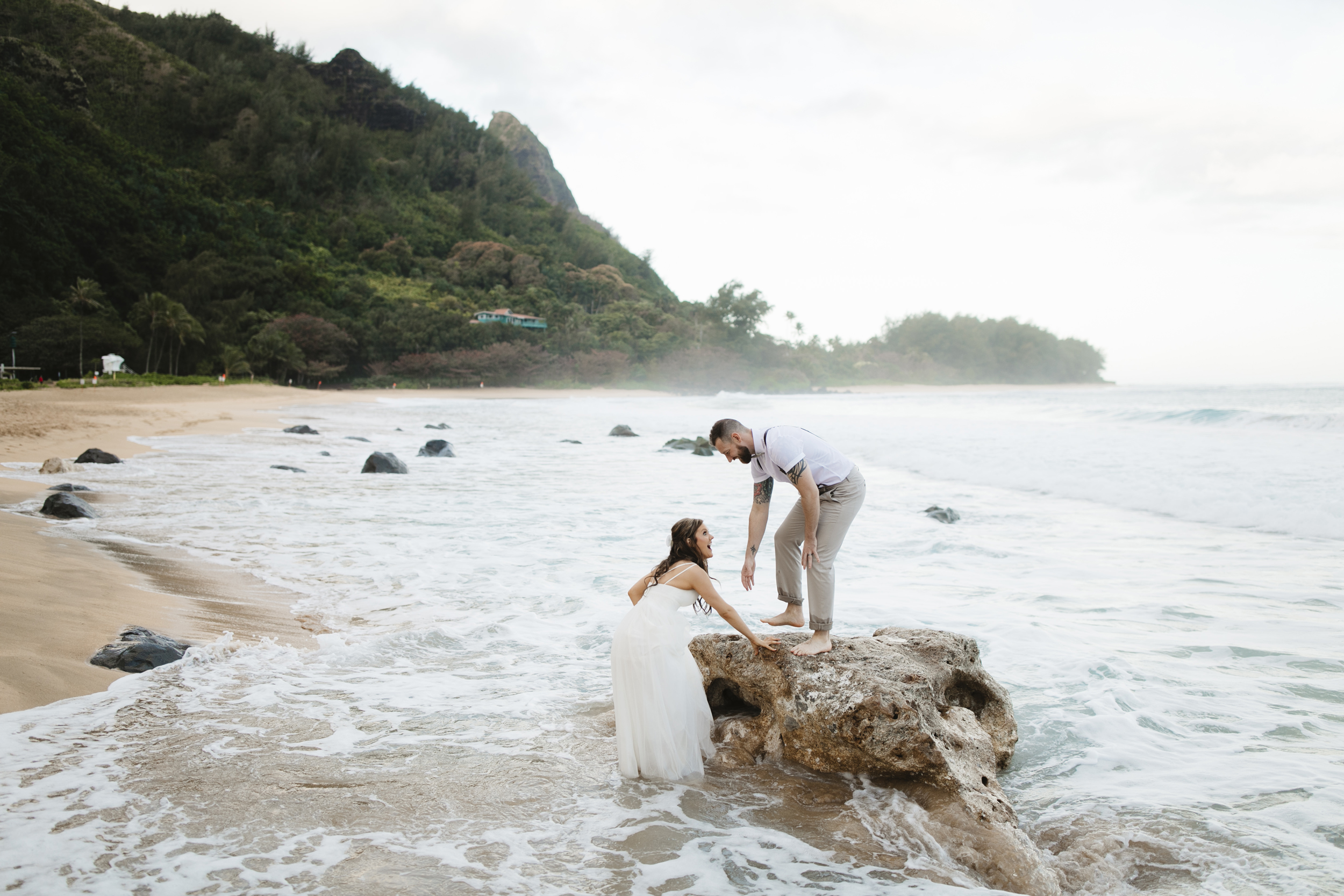 A bride and groom playing on the beach after Tunnels Beach Elopement Ceremony by Kauai Wedding Photographers Colby and Jess