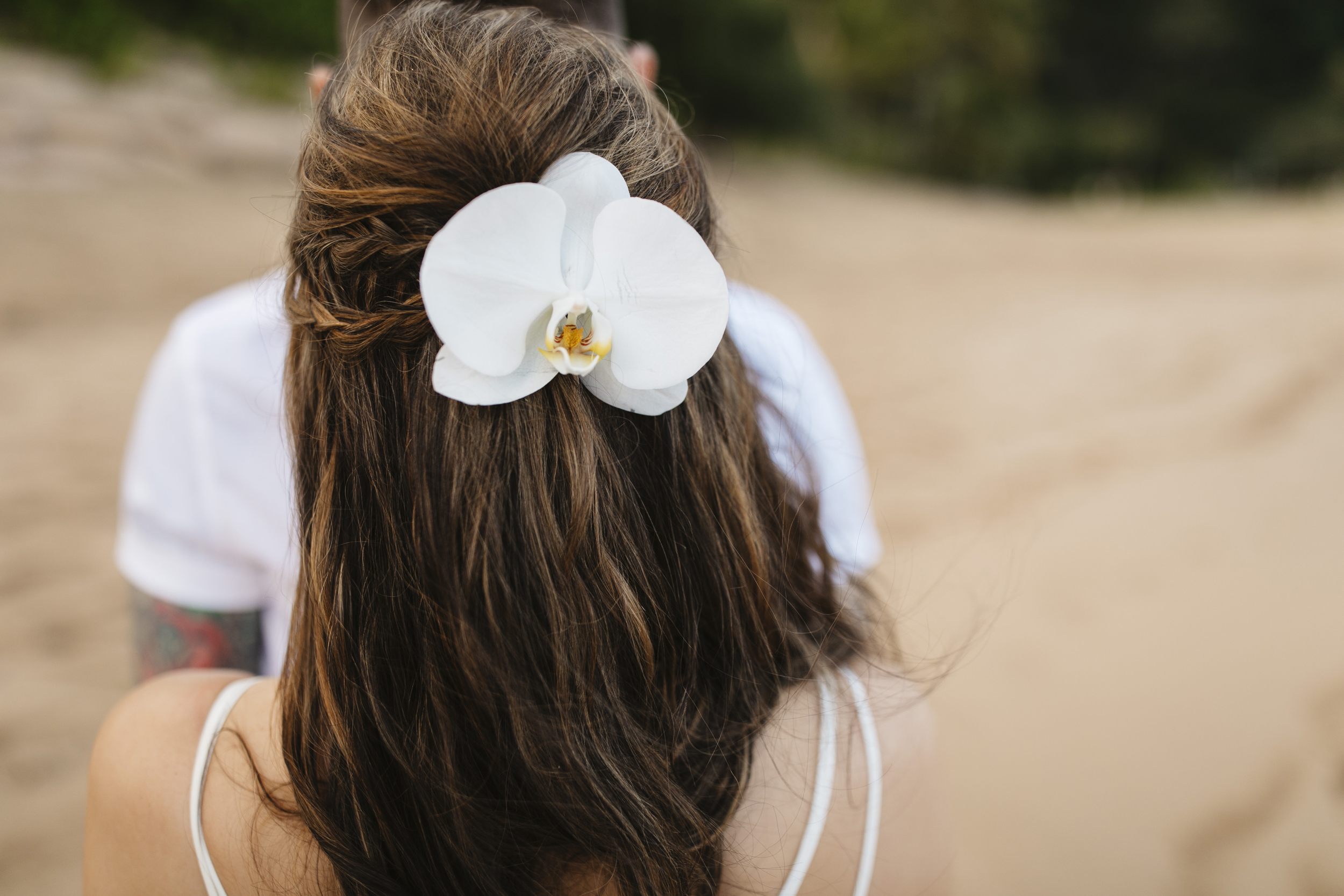 A bride's hair adorned with an orchid flower during her Tunnels beach wedding ceremony with Kauai Elopement Photographers Colby and Jess