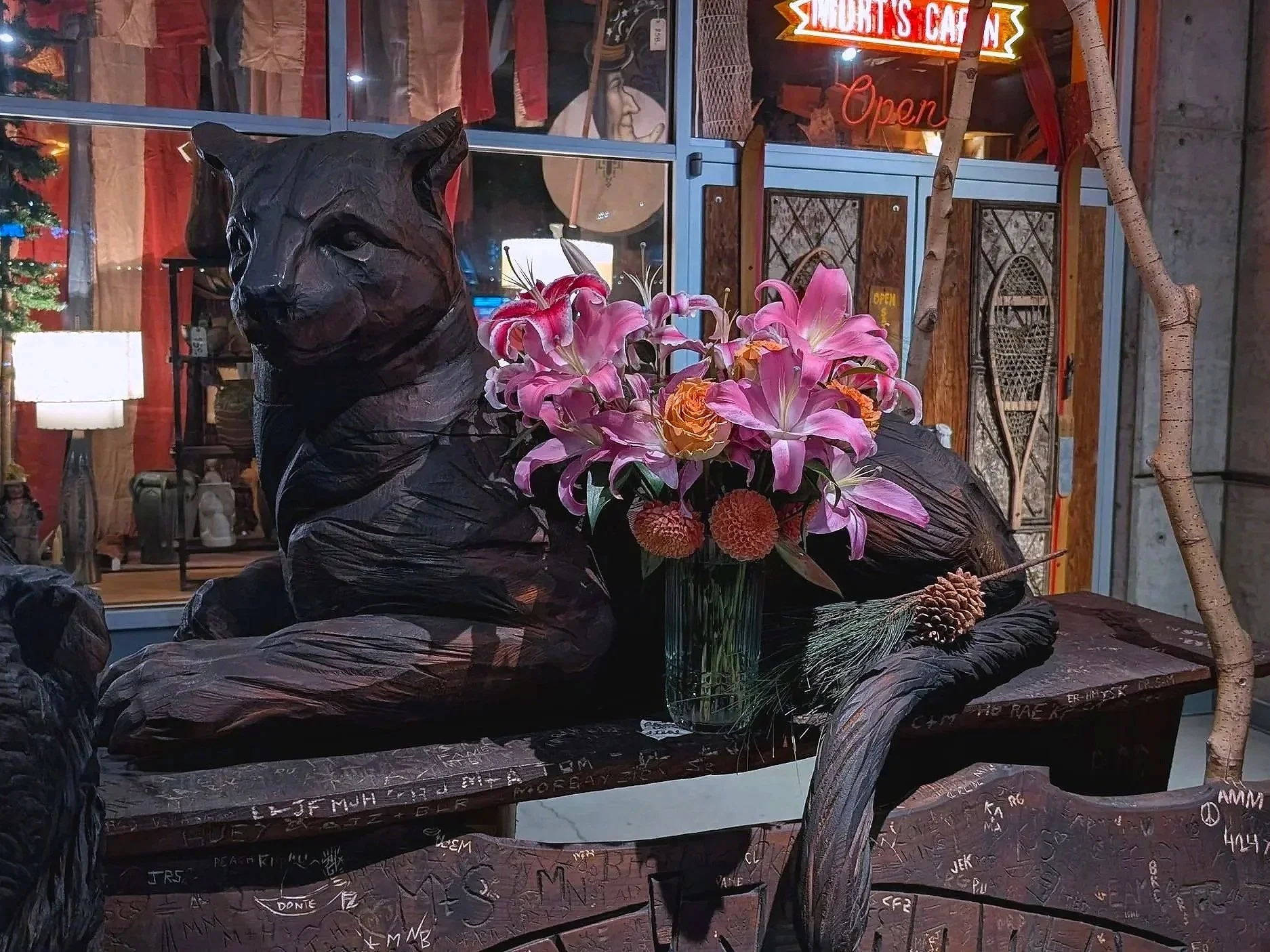 Cougar carved out of wood with a bouquet of fresh flowers beside it