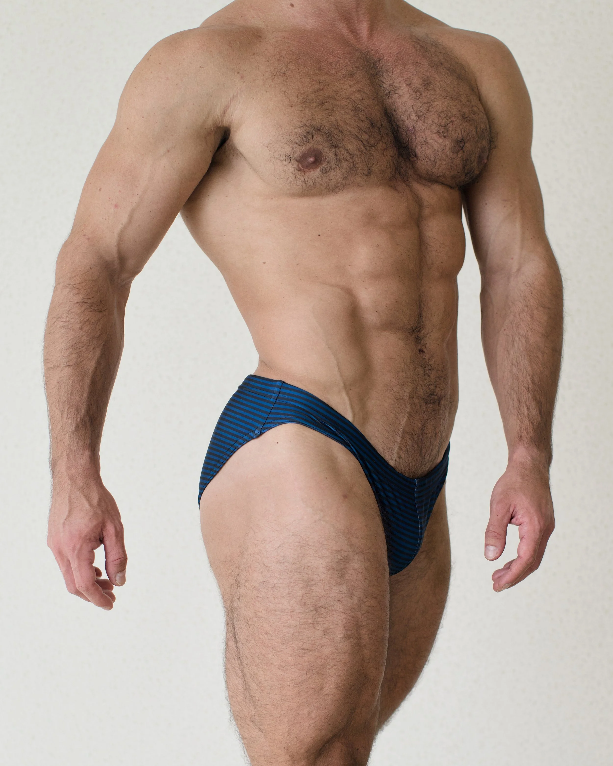 Man seen from the side wearing blue striped Out of Office Caribbean swim brief from Aronik Swim Paradigm collection