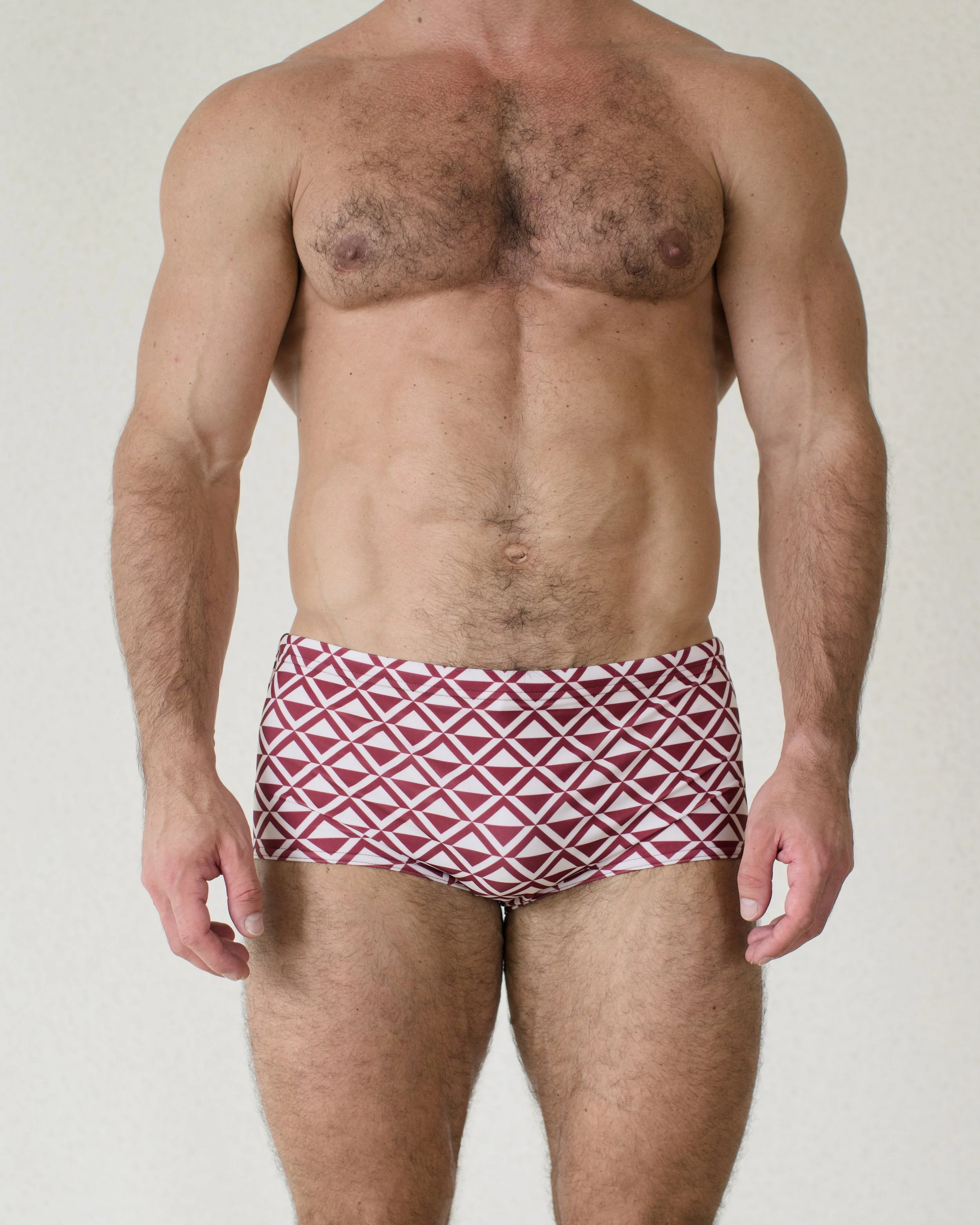 Man seen from front wearing Cherry Paradigm swim sunga featuring red geometric print from Aronik Swim Paradigm Collection