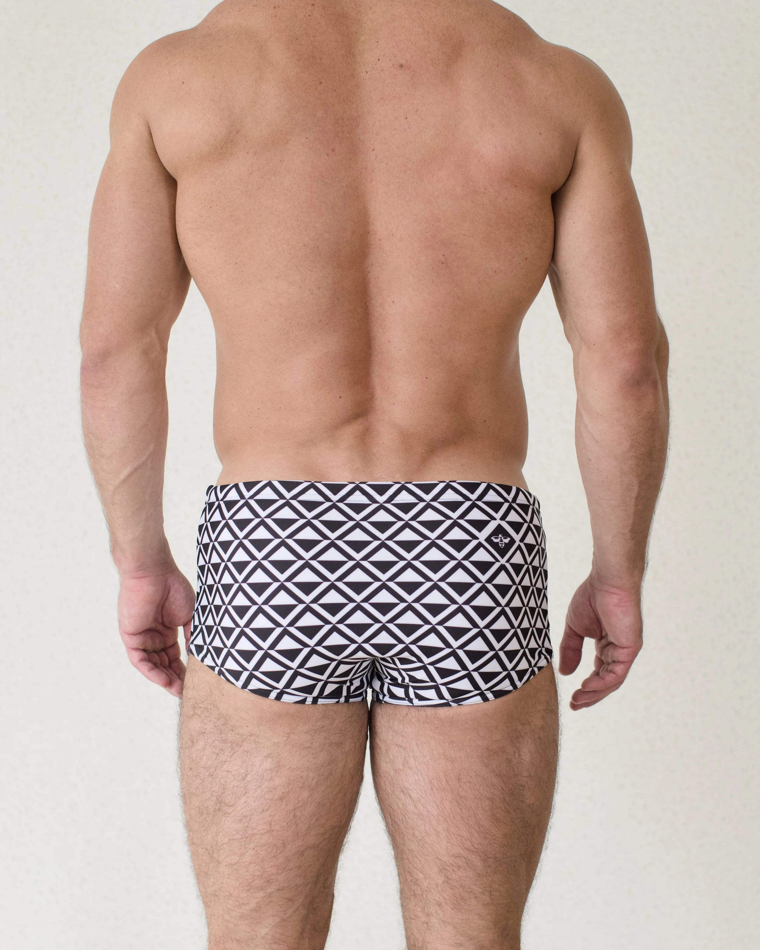 Man seen from back wearing Paradigm swim sunga featuring black geometric print from Aronik Swim Paradigm Collection