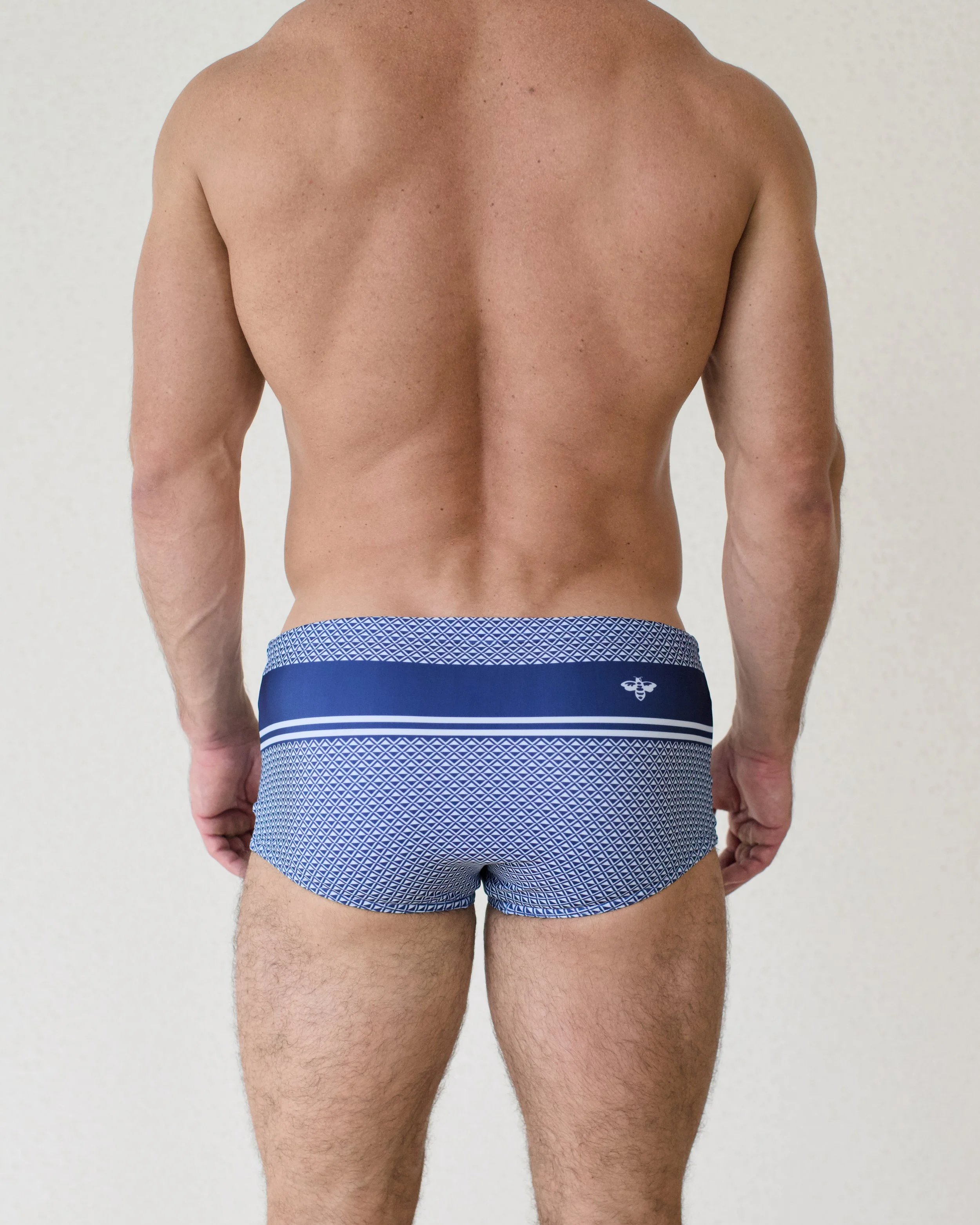 Man seen from back wearing Bastion Mar swim sunga featuring deep blue geometric print from Aronik Swim Paradigm Collection