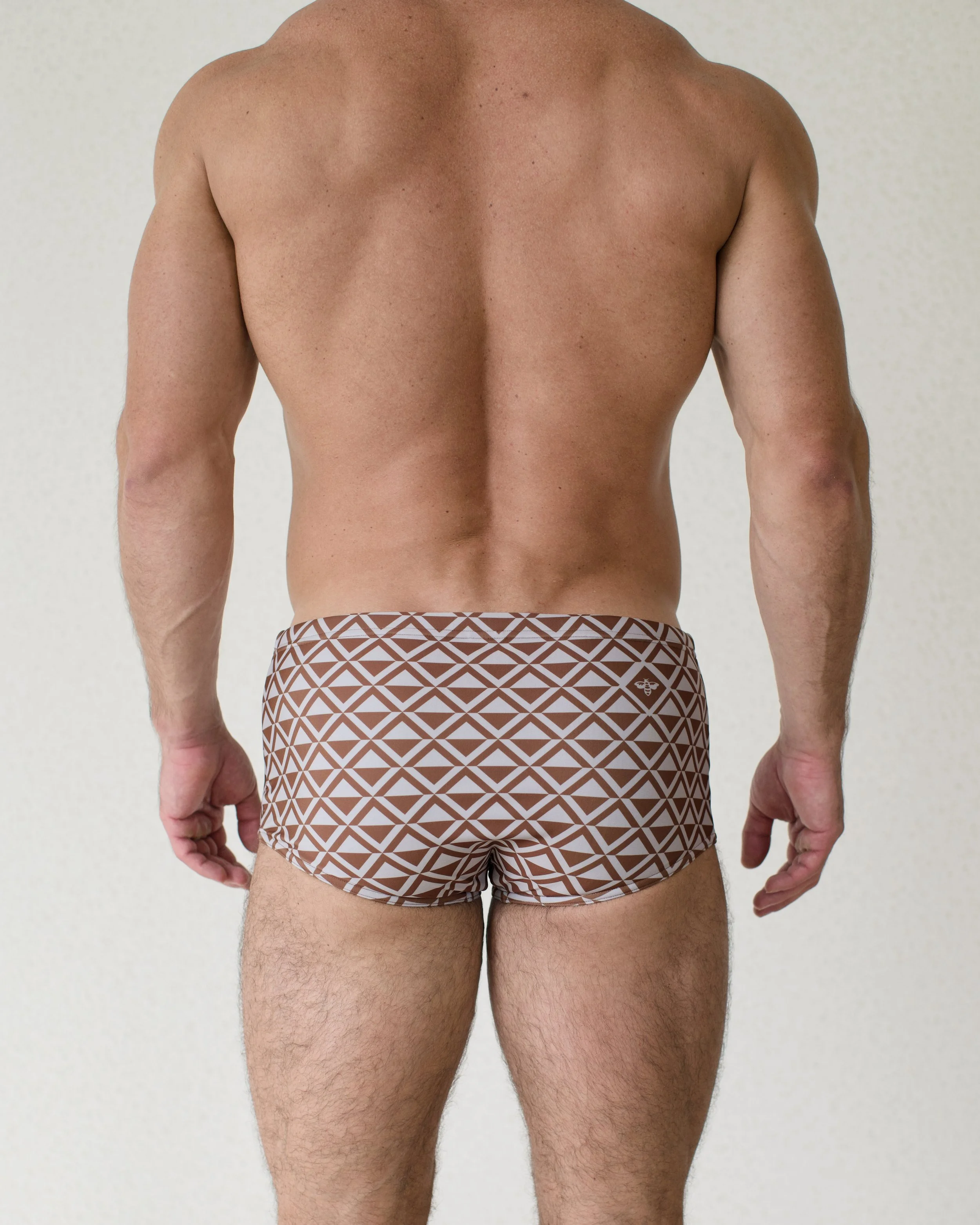 Man seen from back wearing Latte Paradigm swim sunga featuring brown geometric print from Aronik Swim Paradigm Collection