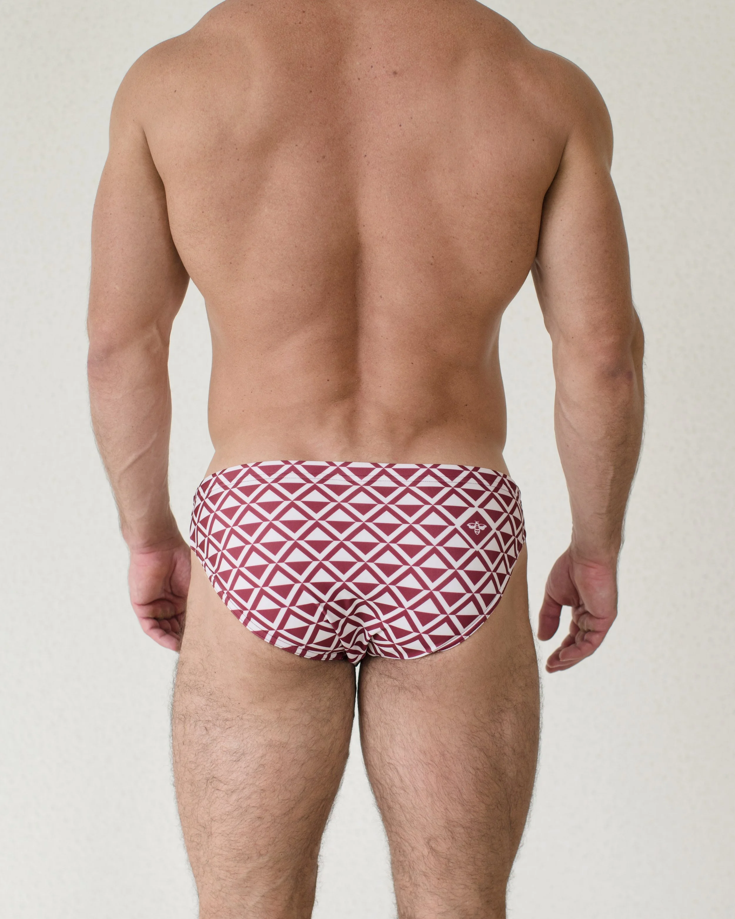 Man seen from back wearing Cherry Paradigm swim bikini featuring red geometric print from Aronik Swim Paradigm Collection