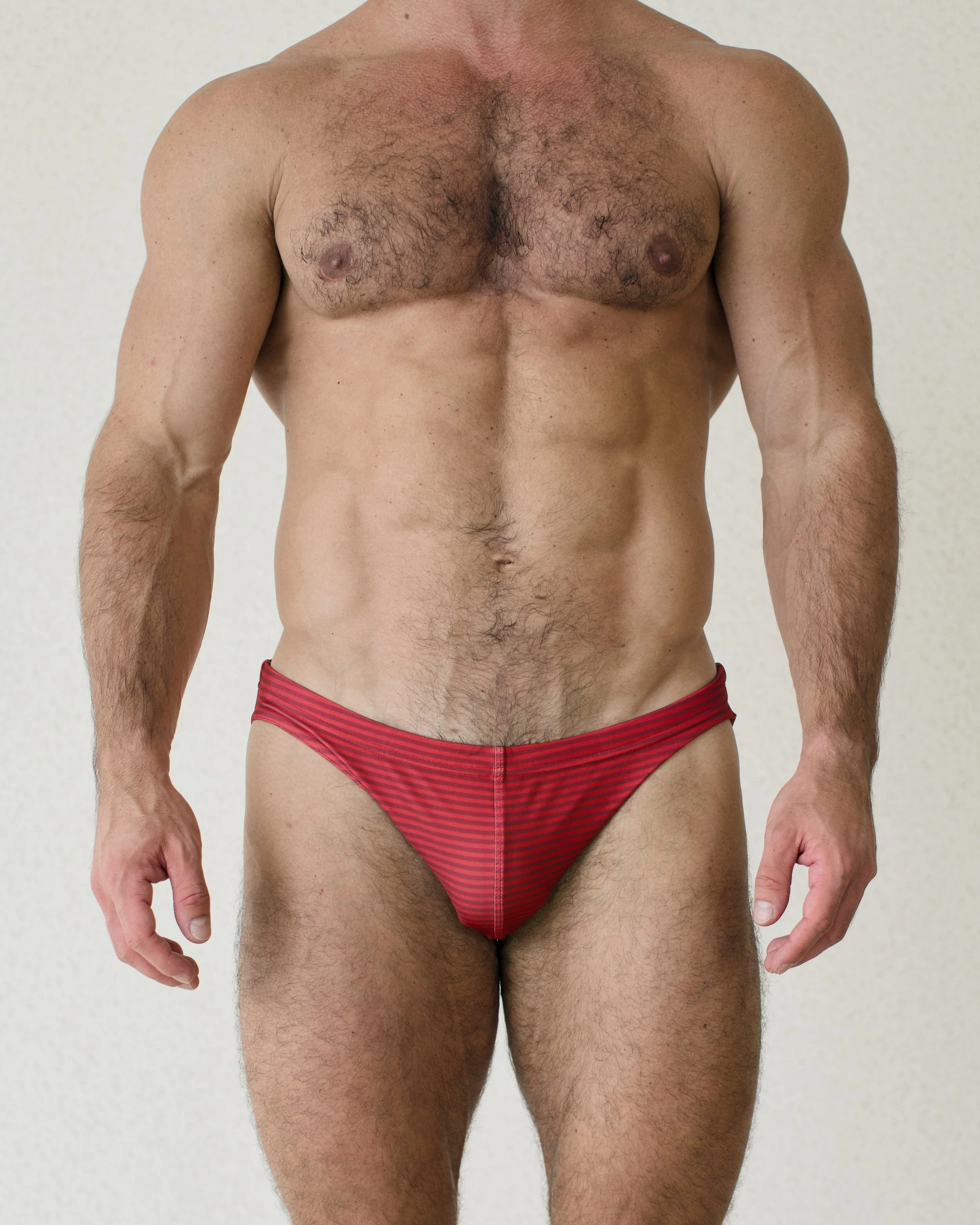 Man seen from the front wearing bold red Out of Office Adventure swim brief from Aronik Swim Paradigm collection