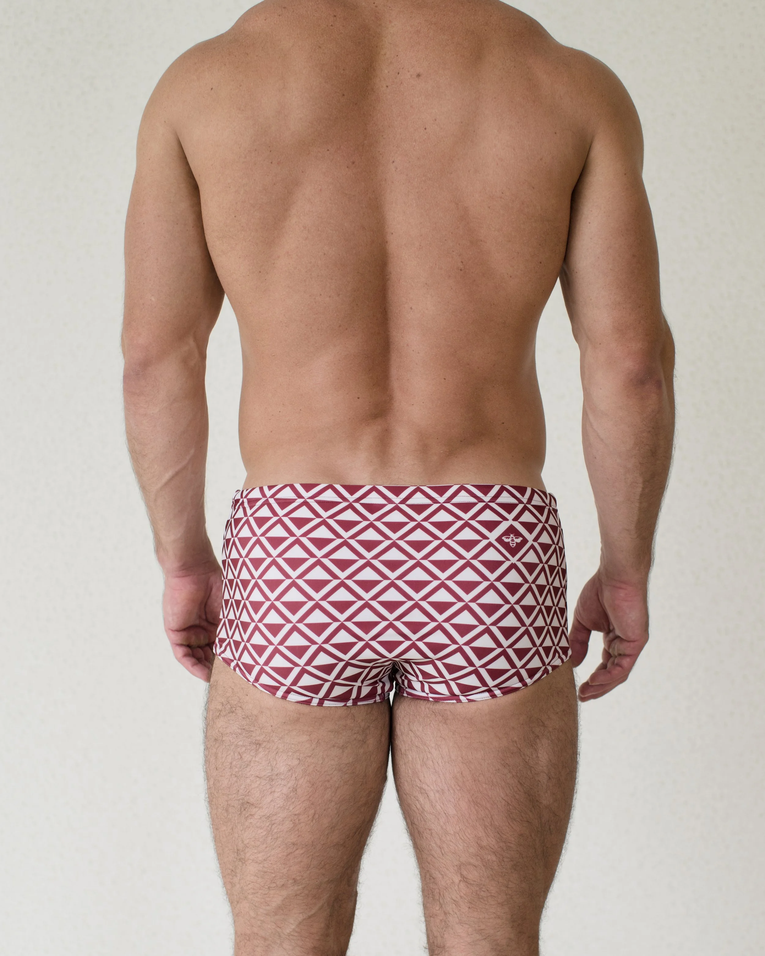 Man seen from back wearing Cherry Paradigm swim sunga featuring red geometric print from Aronik Swim Paradigm Collection