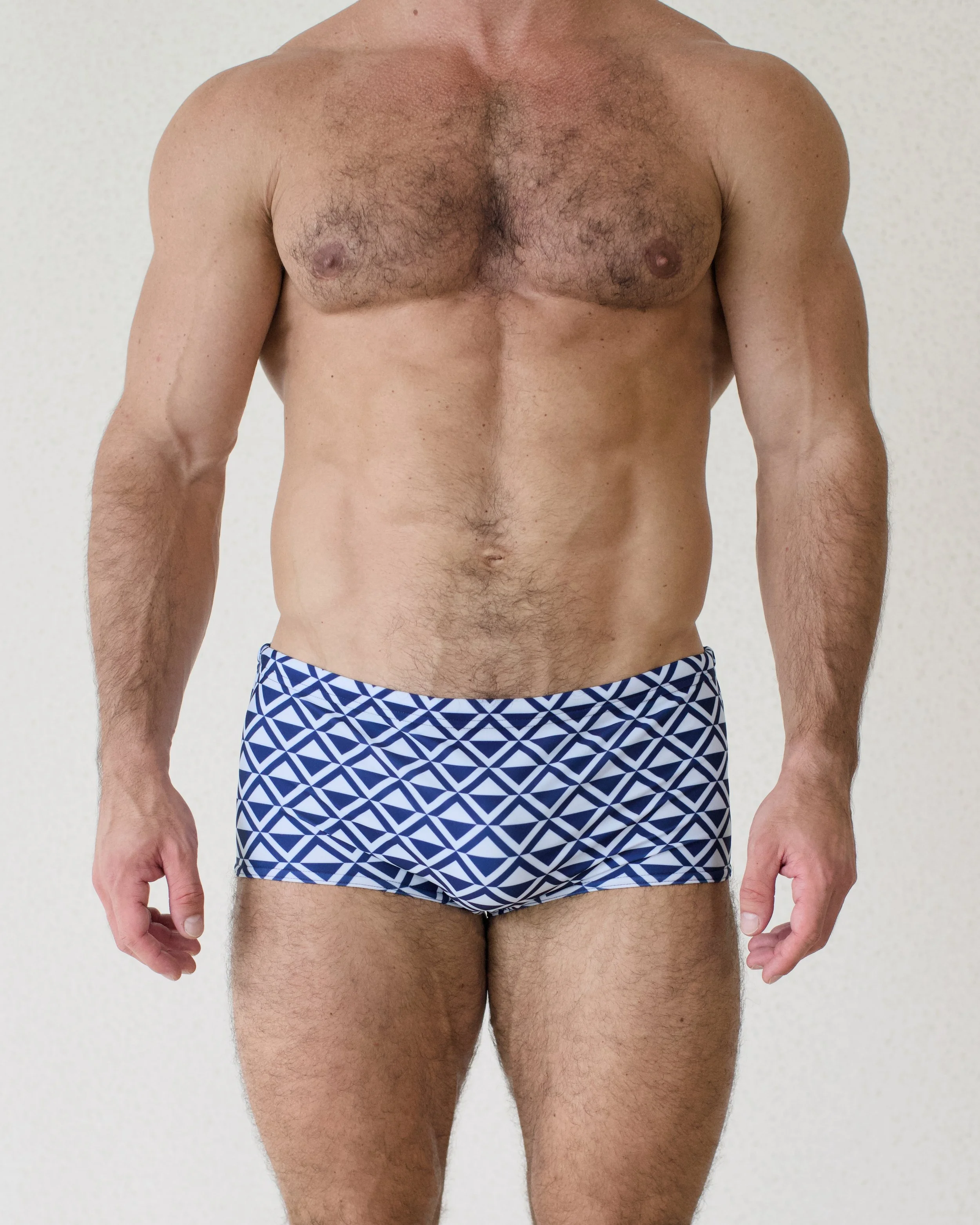 Man seen from front wearing Blu Paradigm swim sunga featuring blue geometric print from Aronik Swim Paradigm Collection