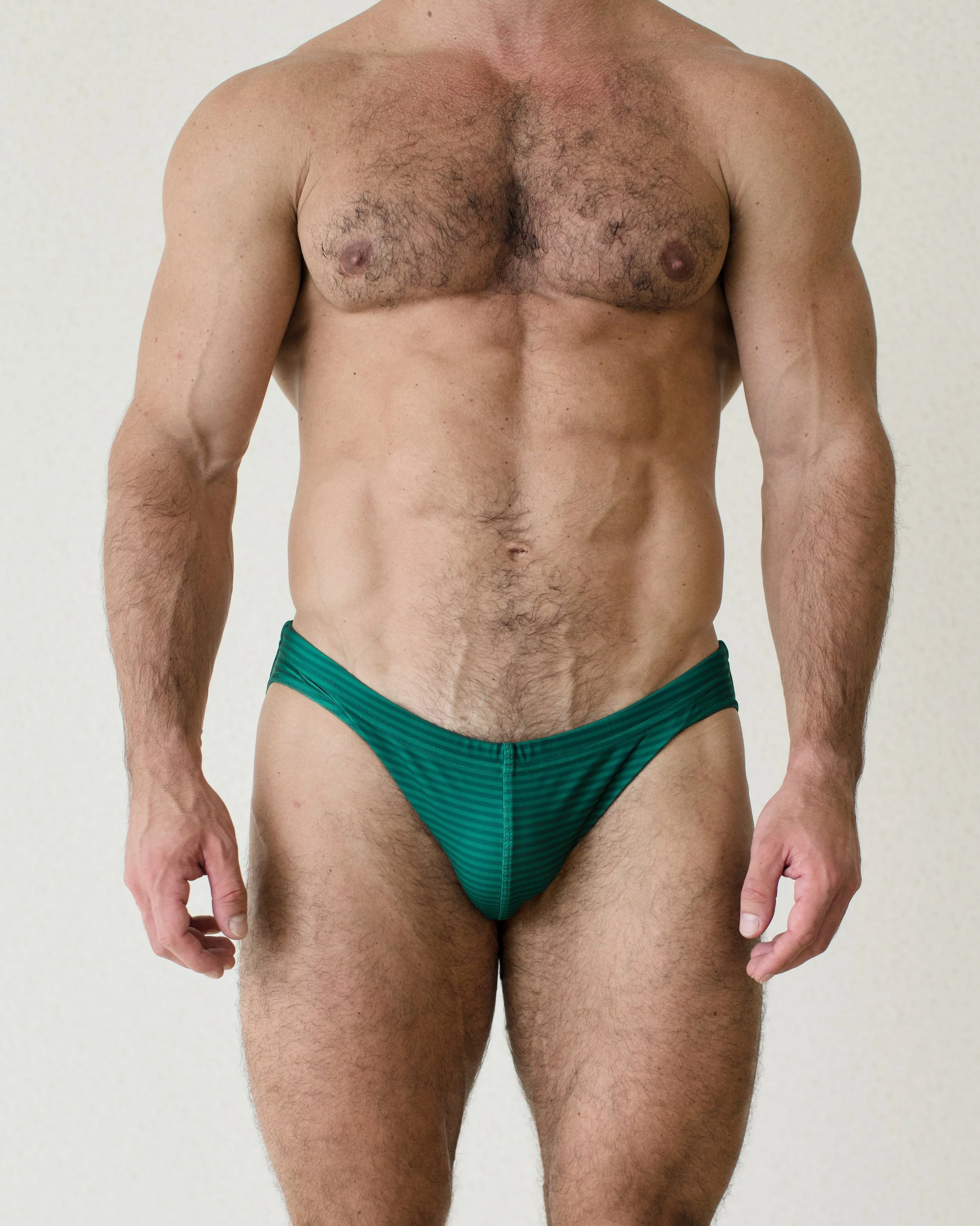 Man seen from the front wearing green Out of Office Mountain swim brief from Aronik Swim Paradigm collection