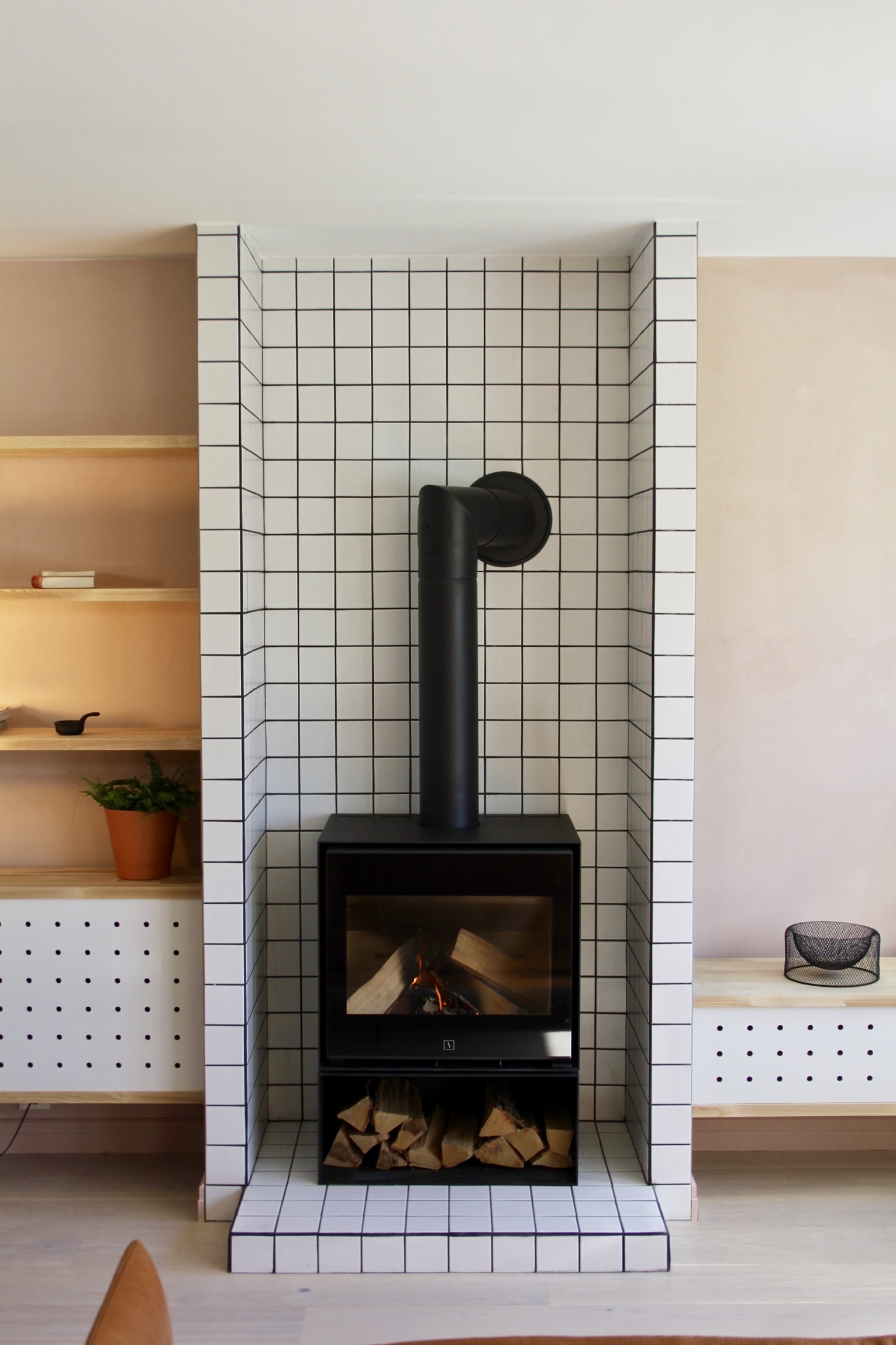  A fireplace was installed surrounded with white tiles, the same as in the kitchen,&nbsp;&nbsp;to protect the surrounding shelves and furniture. 