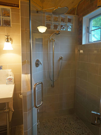 Bathroom design with exposed glass brlocks, brick, and wood, giving it a slightl industrial feel.