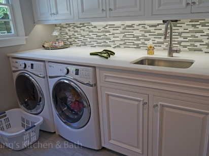 洗衣房设计与柜台下的洗衣机和烘干机和洗衣池。