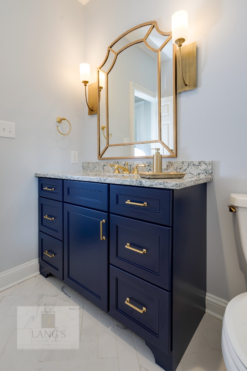 Powder room design with blue vanity and brass fixtures