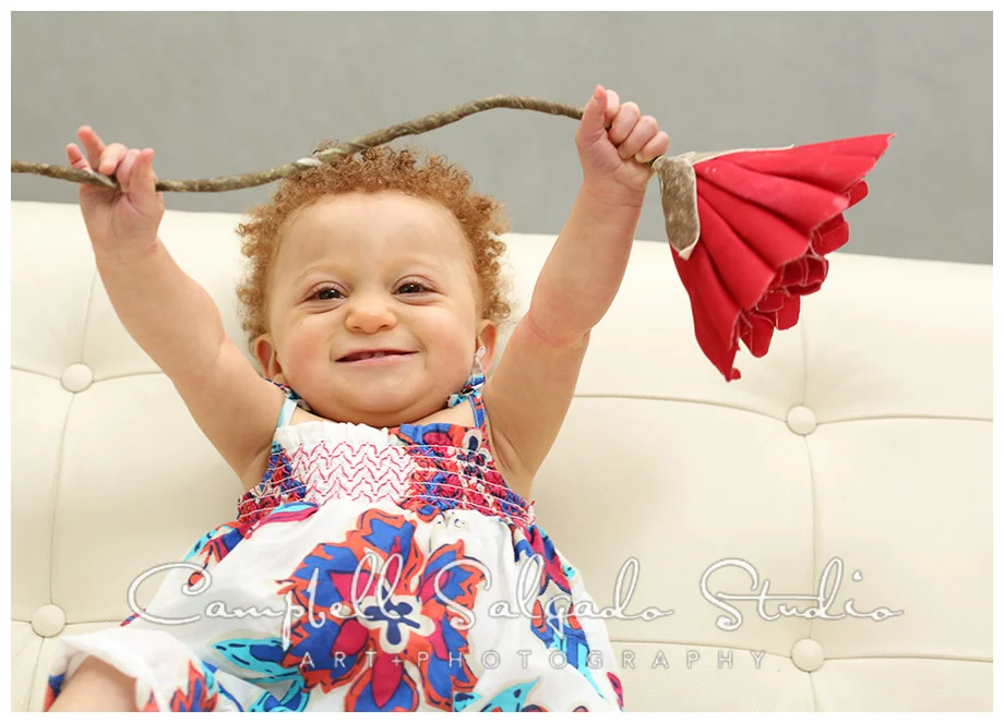 Portrait of baby girl with fake flower by Campbell Salgado Studio.