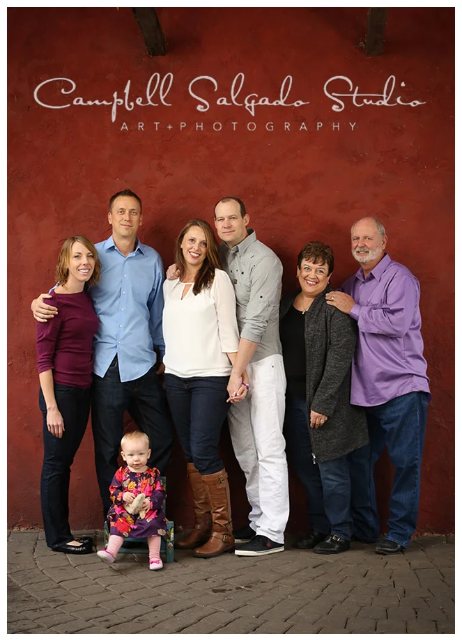 Portrait of extended family on red stucco background in Portland, Oregon at Campbell Salgado Studio.