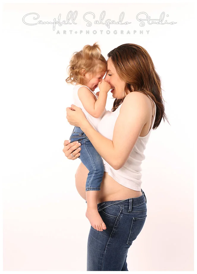 Portrait of pregnant woman and her daughter on white background by Portland photographers Campbell and Salgado.