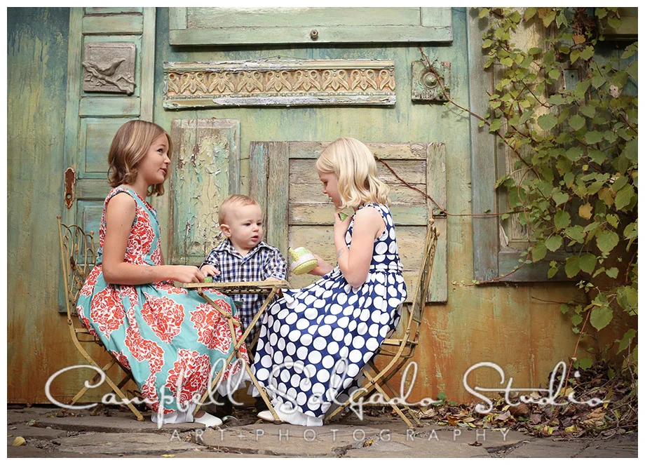 Portrait of kids having a tea party on vintage doors background at Campbell Salgado Studio.