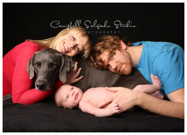 Portrait of new family with dog at Campbell Salgado Studio on black background.