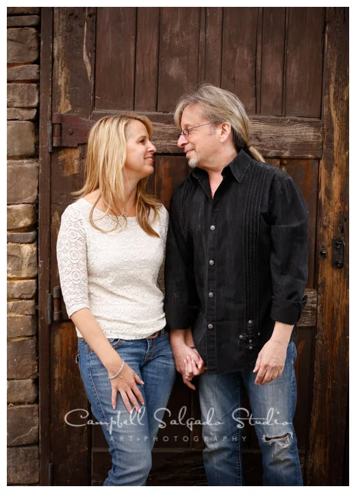 Portrait of couple on rustic door at Campbell Salgado Studio.