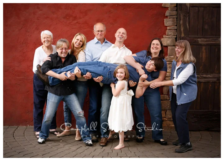 Portrait of extended family on red stucco background at Campbell Salgado Studio.
