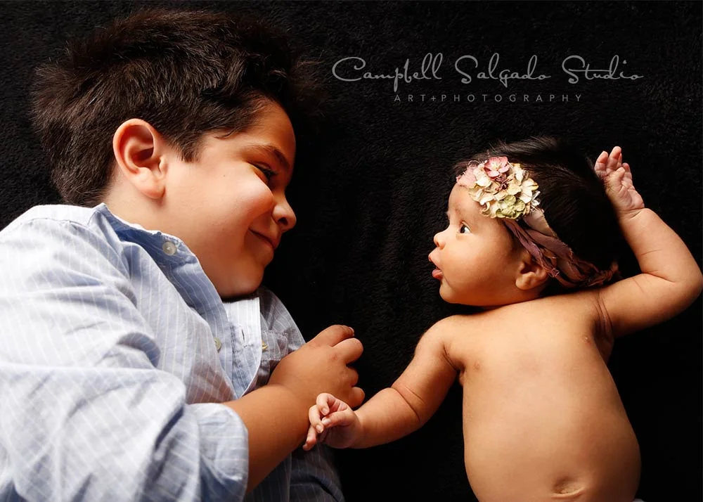 Newborn photography—5 year old boy smiling at one month old sister—by Portland, Oregon newborn photographers at Campbell Salgado Studio.