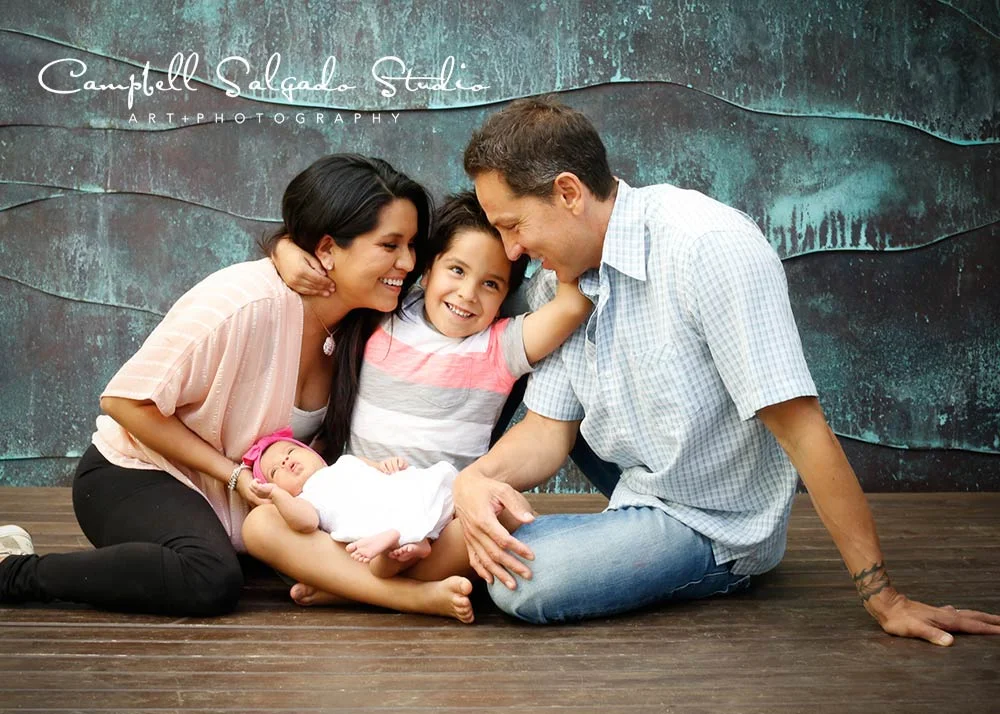 Family photography—5 year old boy hugging parents and holding newborn sister—by Portland, Oregon family photographers at Campbell Salgado Studio.