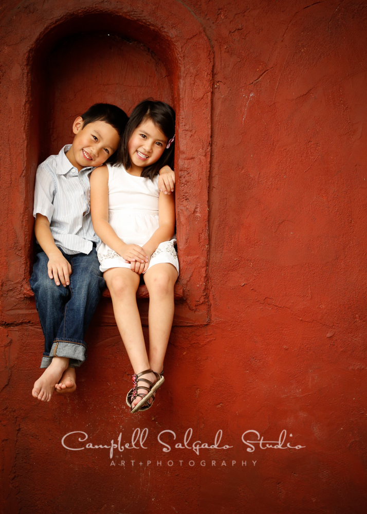  Portrait of twins on red stucco background by childrens photographers at Campbell Salgado Studio, Portland, Oregon. 