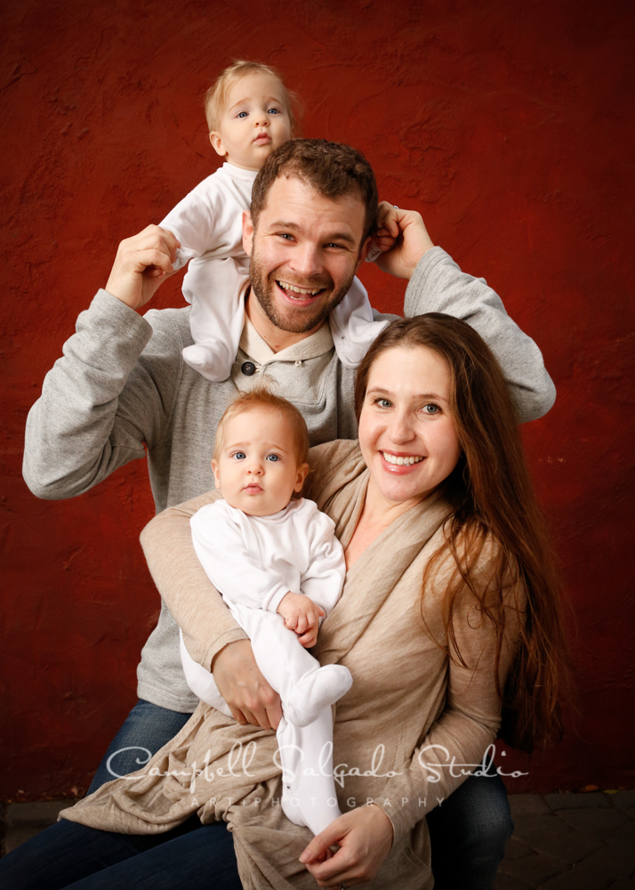  Portrait of family on red stucco background&nbsp;by family photographers at Campbell Salgado Studio, Portland, Oregon. 