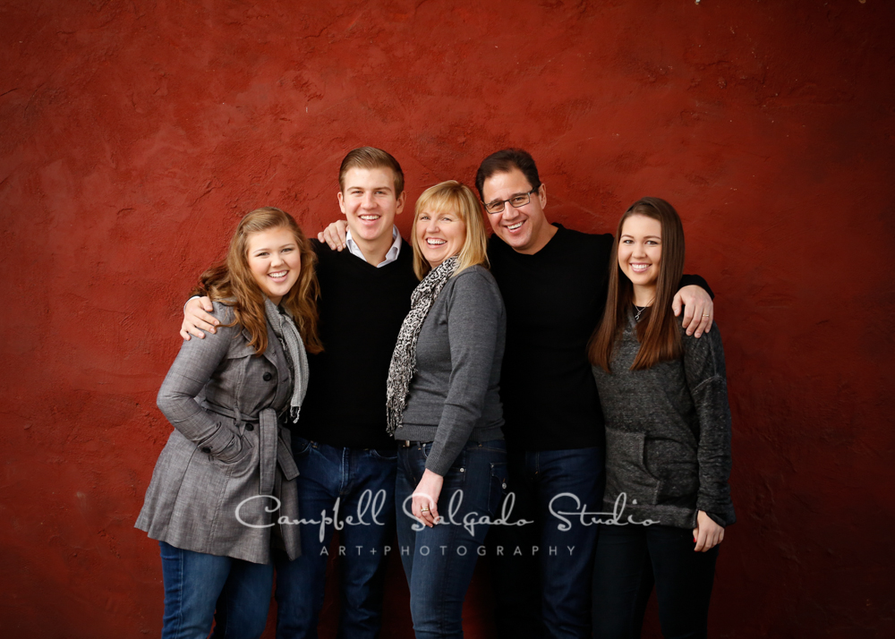  Portrait of family on red stucco background by family photographers at Campbell Salgado Studio, Portland, Oregon. 