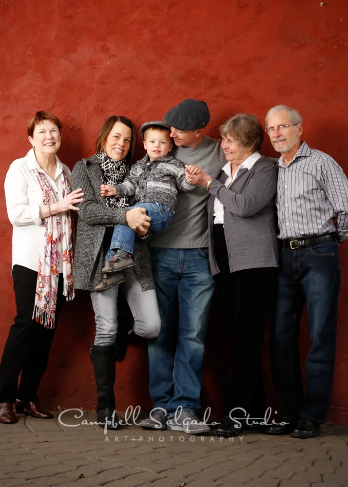 Portrait of family on red stucco background by family photographers at Campbell Salgado Studio, Portland, Oregon.