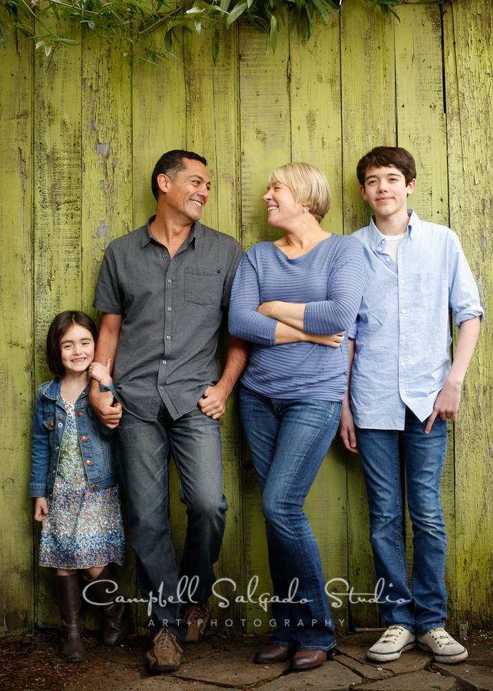  Portrait of family on green fence boards&nbsp;background&nbsp;by family photographers at Campbell Salgado Studio, Portland, Oregon. 