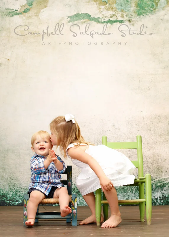 Portrait of a sister kissing baby brother by children's photographers at Campbell Salgado Studio, Portland, Oregon