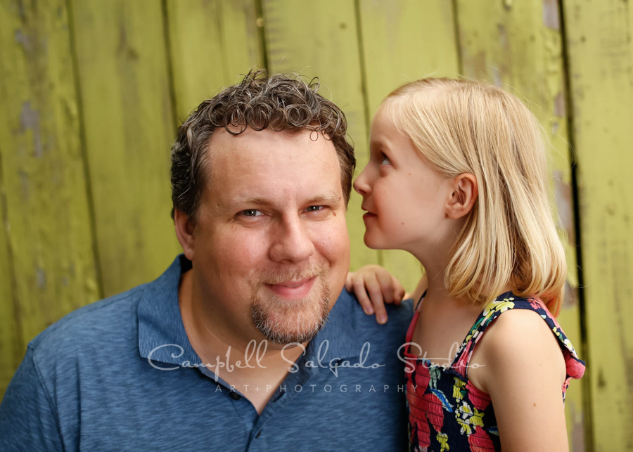  Portrait of father and daughter on lime fenceboards&nbsp;background by family photographers at Campbell Salgado Studio in Portland, Oregon. 