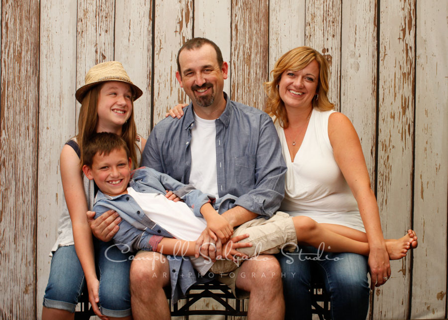  Portrait of family on white fenceboards background by family photographers at Campbell Salgado Studio in Portland, Oregon. 