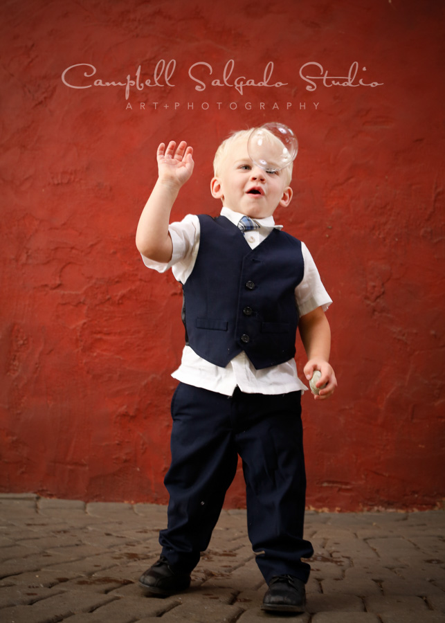  Portrait of toddler on red stucco background by children's photographers at Campbell Salgado Studio in Portland, Oregon. 