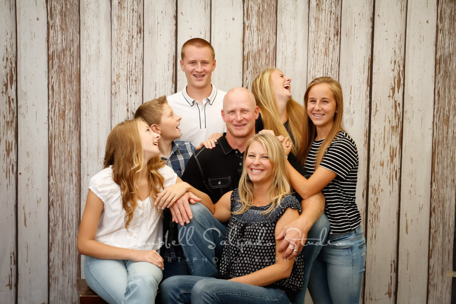  Portrait of family on white fence boards background by family photographers at Campbell Salgado Studio in Portland, Oregon. 