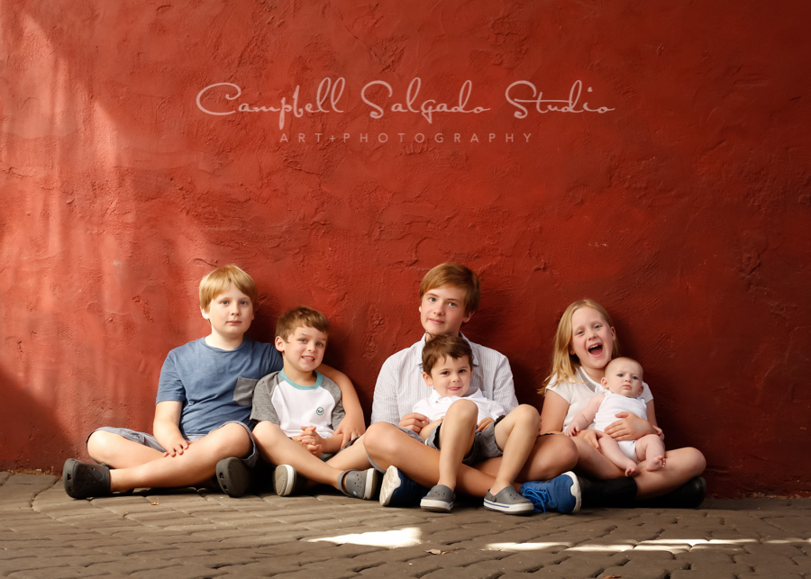  Portrait of children on red stucco background by children's photographers at Campbell Salgado Studio in Portland, Oregon. 