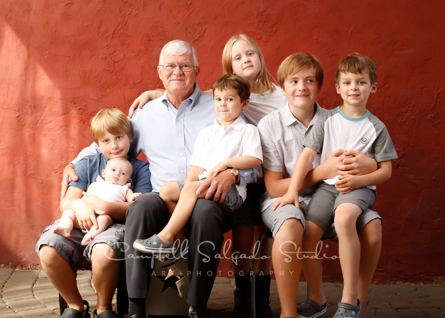  Portrait of multi-generational family on red stucco background by family photographers at Campbell Salgado Studio in Portland, Oregon. 