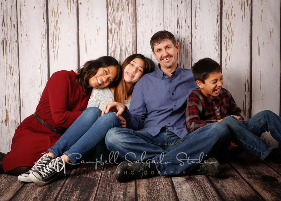Portrait of family on white fenceboards background by family photographers at Campbell Salgado Studio in Portland, Oregon.