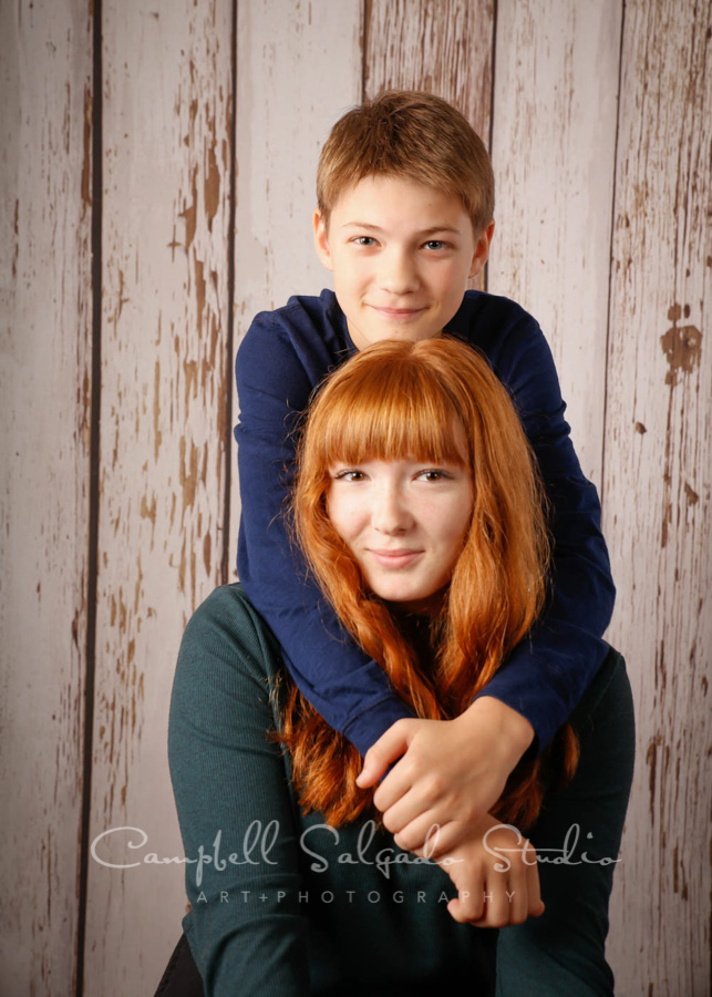  Portrait of siblings on white fence boards background by teen photographers at Campbell Salgado Studio in Portland, Oregon. 