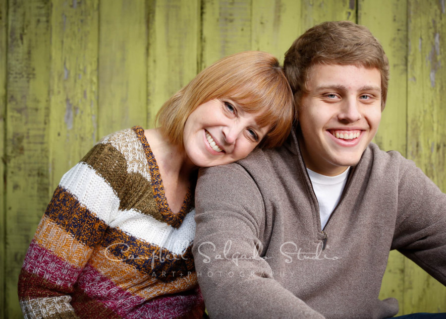  Portrait of mother and son on lime fence boards background by family photographers at Campbell Salgado Studio in Portland, Oregon. 