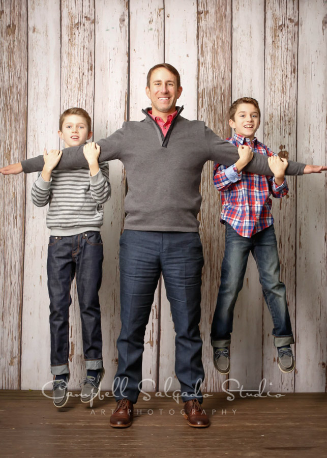  Portrait of dad and boys on white fence boards background by family photographers at Campbell Salgado Studio in Portland, Oregon. 