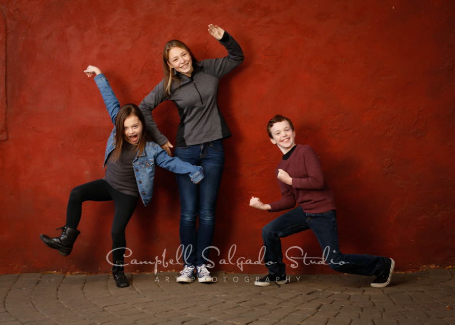  Portrait of children on red stucco background by children's photographers at Campbell Salgado Studio in Portland, Oregon. 
