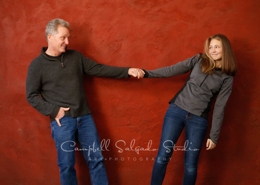  Portrait of father and daughter on red stucco background by family photographers at Campbell Salgado Studio in Portland, Oregon. 